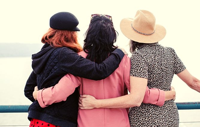 Three women from the back, with arms around each other
