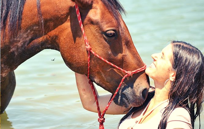Jill in the water with a horse, face to face